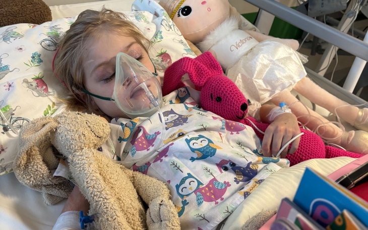Dziewczynka w szpitalu z maską tlenową i pluszakami.