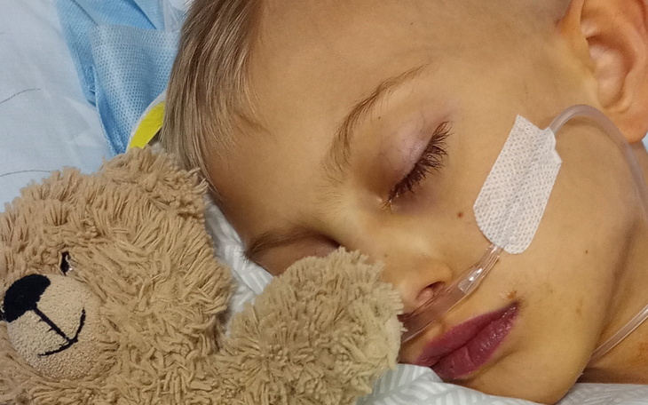 Chłopiec śpiący w szpitalu z pluszowym misiem.