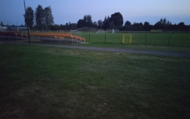 Pusty stadion piłkarski o zmierzchu, z trybunami.