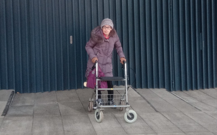 Kobieta z wózkiem inwalidzkim, poruszająca się na zewnątrz.