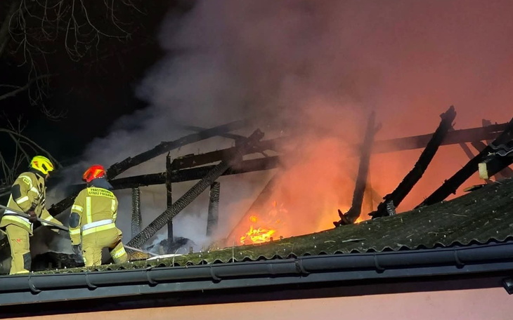 Działacze gaśniczy gaszą pożar w zgliszczach spalonego budynku, akcja ratunkowa w nocy.