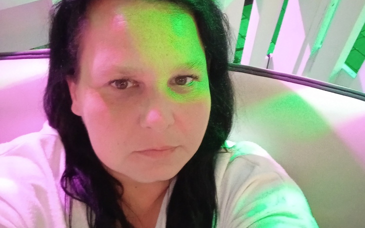 Kobieta z długimi włosami, selfie w kolorowym świetle.