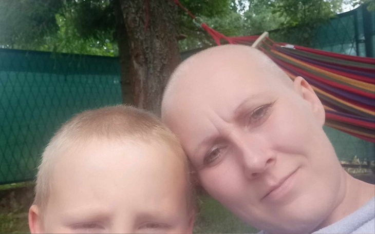 Kobieta z krótkimi włosami i dzieckiem na tle hamaka.