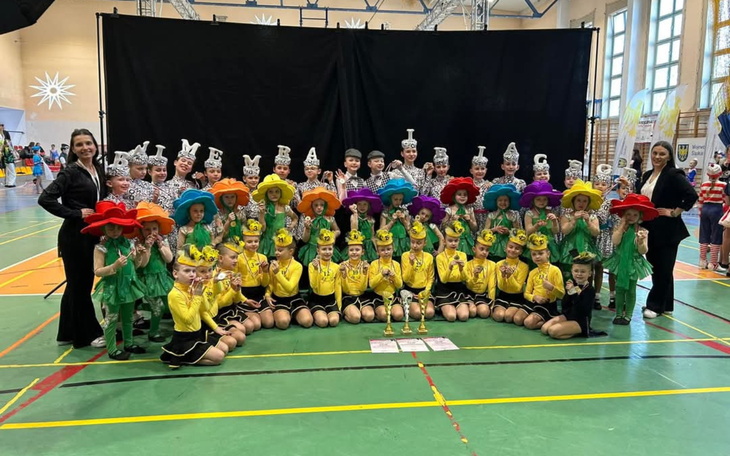 Grupa dzieci w kolorowych strojach, pozująca do zdjęcia.