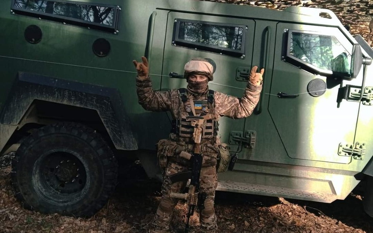 Żołnierz w mundurze, pozujący obok pojazdu wojskowego.