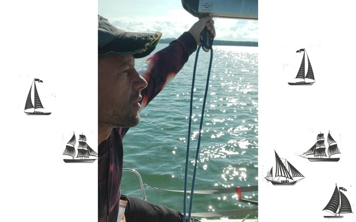 Mężczyzna na łodzi trzyma linę, w tle odbicie słońca w wodzie.