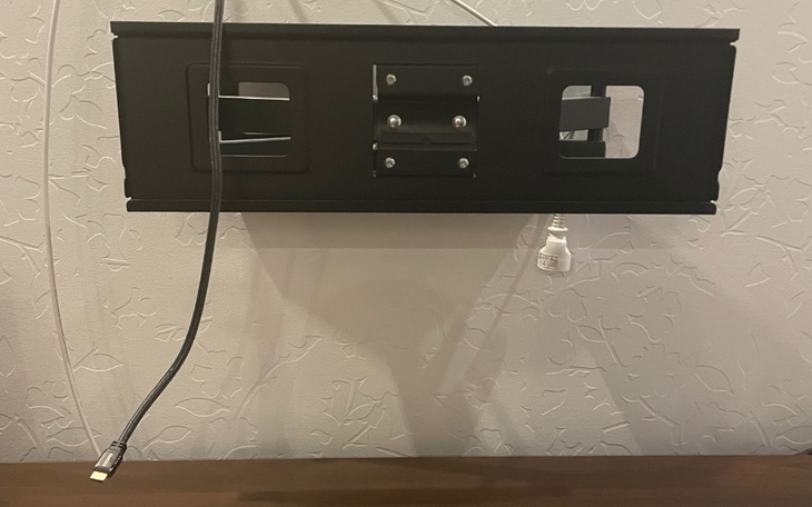 Czarna skrzynka z otworami i kablami na ścianie.