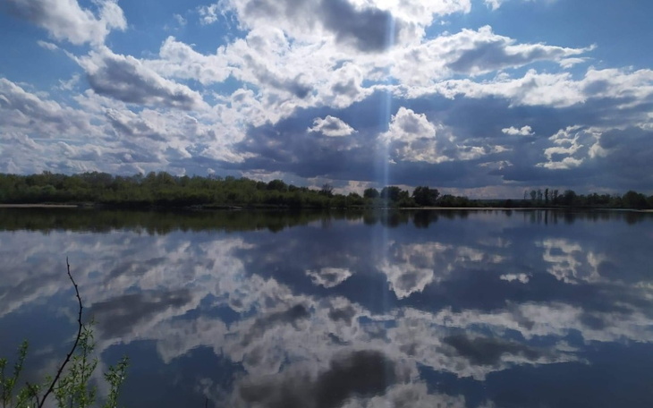 Spokojny widok na jezioro z odbiciem chmur w wodzie.