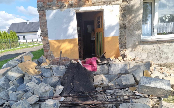 Zniszczona ściana budynku z odsłoniętymi cegłami i gruzem.