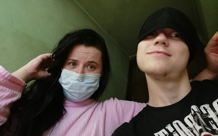 Młoda para w maseczkach, pozująca do zdjęcia w pomieszczeniu.