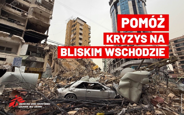 Zniszczony budynek po katastrofie, z wrakiem samochodu w tle.