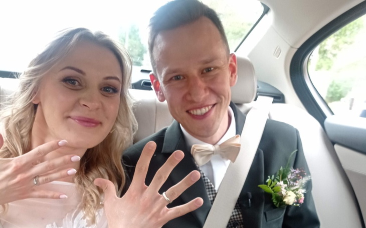 Młoda para w samochodzie, pokazująca obrączki.