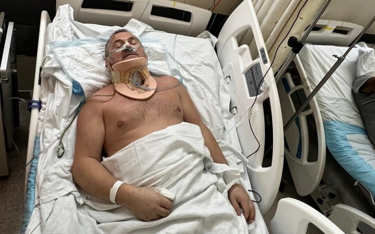 Mężczyzna w szpitalnym łóżku, z unieruchomioną szyją.