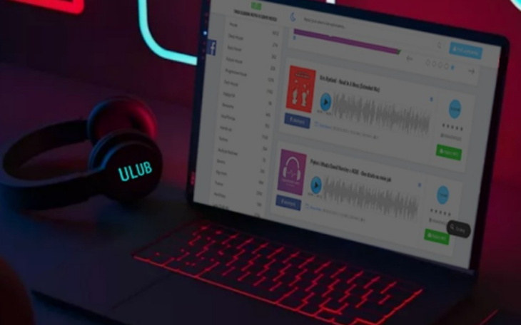 Laptop z aplikacją muzyczną i słuchawkami na tle neonów.