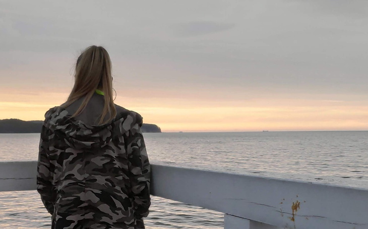 Osoba na molo, podziwiająca zachód słońca nad morzem.