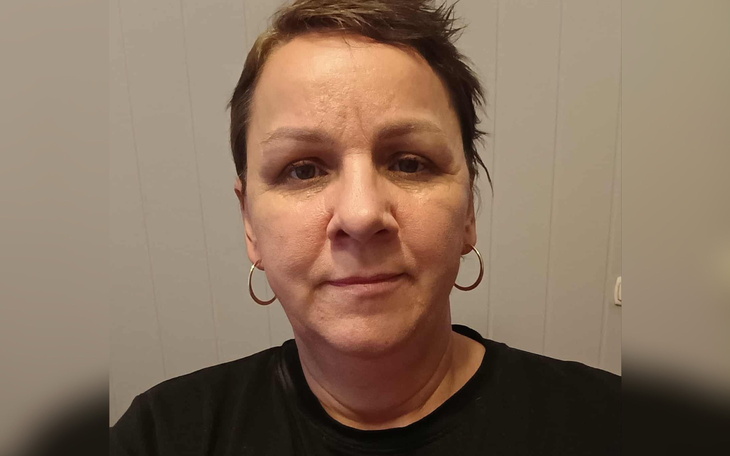 Portret kobiety z krótkimi włosami, w czarnej koszulce, z kolczykami w uszach.