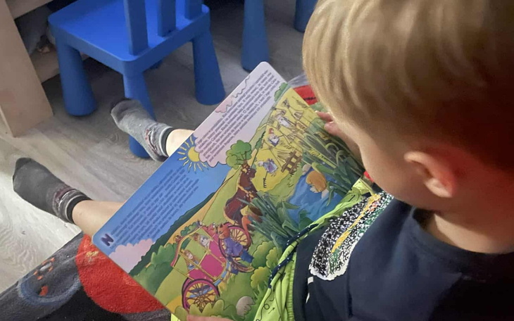 Chłopiec czyta książkę, siedząc na podłodze.