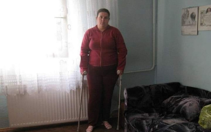 Kobieta z kulami w pokoju, przy oknie.