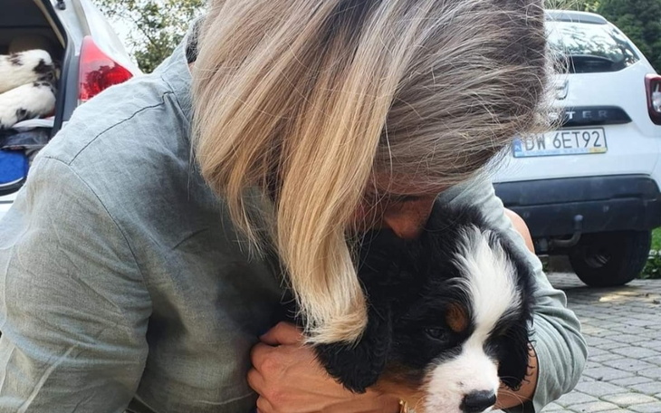 Kobieta przytula szczeniaka, okazując mu miłość i troskę.