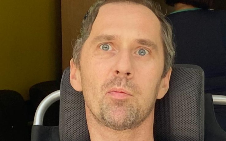 Mężczyzna w wózku inwalidzkim, z wyrazem twarzy pełnym emocji.