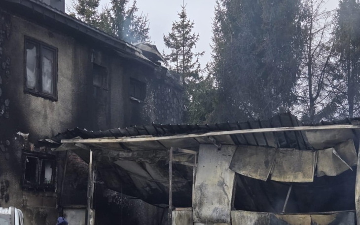 Zniszczony budynek po pożarze, z dymem i zniszczeniami.