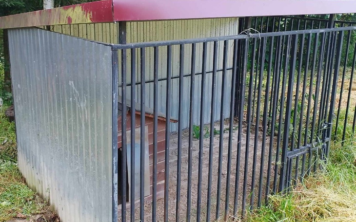 Klatka dla zwierząt w lesie, z metalowymi prętami.