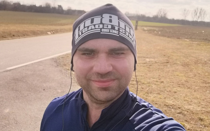 Mężczyzna w czapce biegowy na drodze w słoneczny dzień.