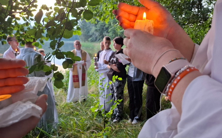 Osoby trzymające świece podczas ceremonii na łonie natury.