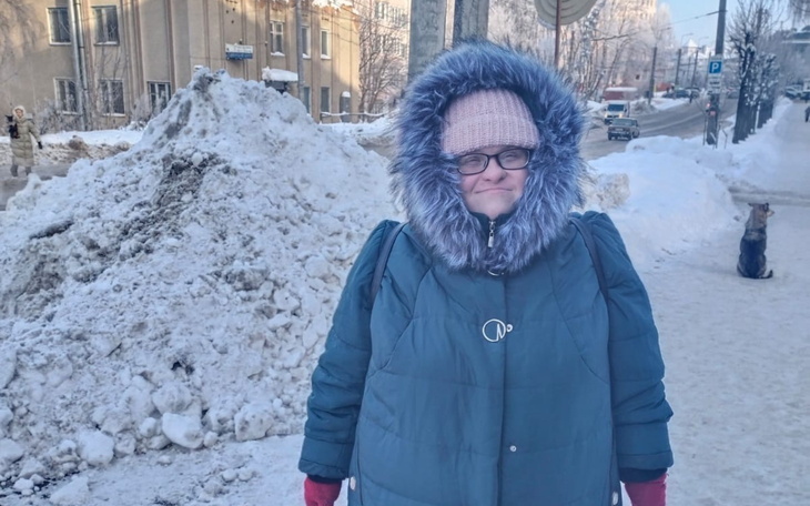 Kobieta w zimowej kurtce na tle zasypanej śniegiem ulicy.