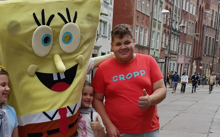 Chłopiec z postacią SpongeBoba, oboje uśmiechnięci na ulicy.