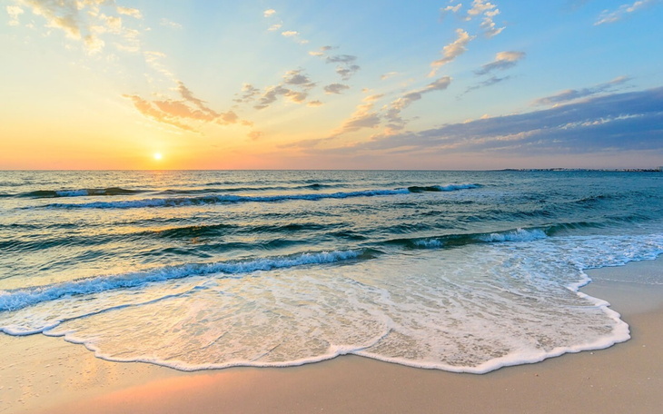 Widok na morze podczas zachodu słońca, spokojne fale i piękne chmury.