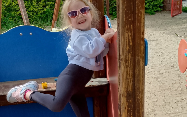 Mała dziewczynka bawiąca się na placu zabaw, radosny uśmiech.