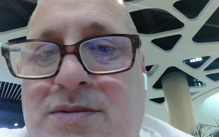 Mężczyzna w okularach, selfie w nowoczesnym wnętrzu.