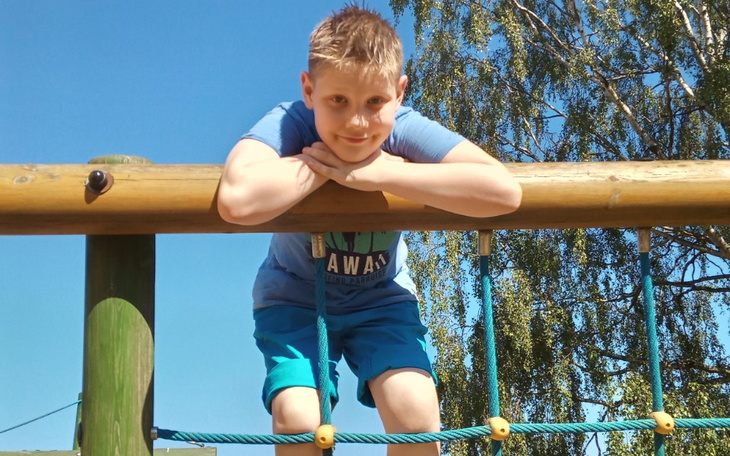 Chłopiec bawiący się na placu zabaw, uśmiechnięty i radosny.