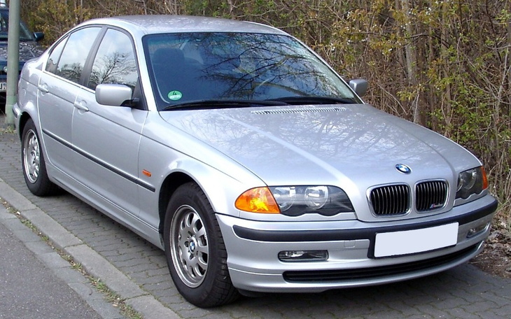 Srebrny samochód marki BMW zaparkowany przy drodze.
