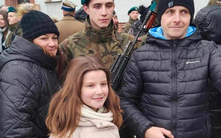 Rodzina pozująca do zdjęcia z żołnierzem w mundurze.