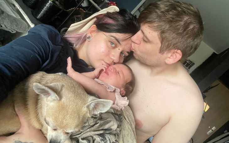 Rodzina z noworodkiem i psem, spędzająca czas razem w domu.