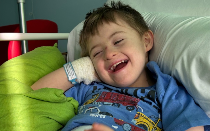 Uśmiechnięty chłopiec w szpitalu, z opatrunkiem na ręce.