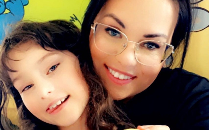 Uśmiechnięta matka z dzieckiem, obie pozują do zdjęcia.