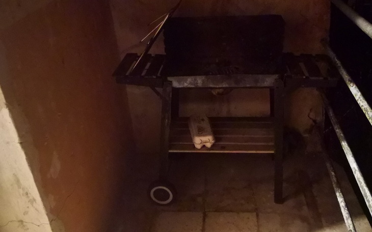 Stary grill w ciemnym pomieszczeniu, z widoczną półką.