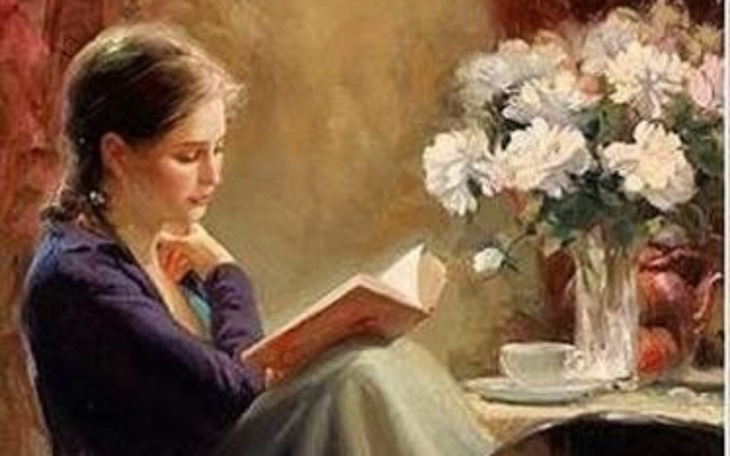 Młoda dziewczyna czytająca książkę przy stole.