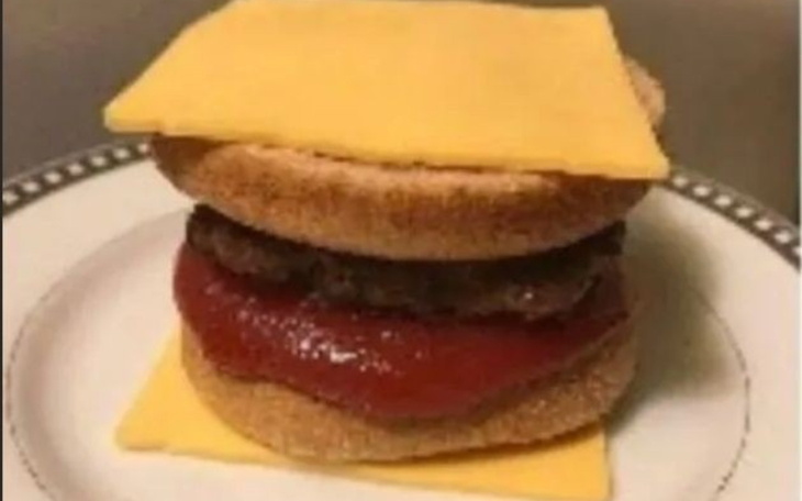 Kanapka z hamburgerem, serem i ketchupem na talerzu.