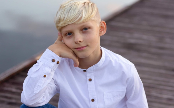 Chłopiec w białej koszuli, pozujący na pomoście.