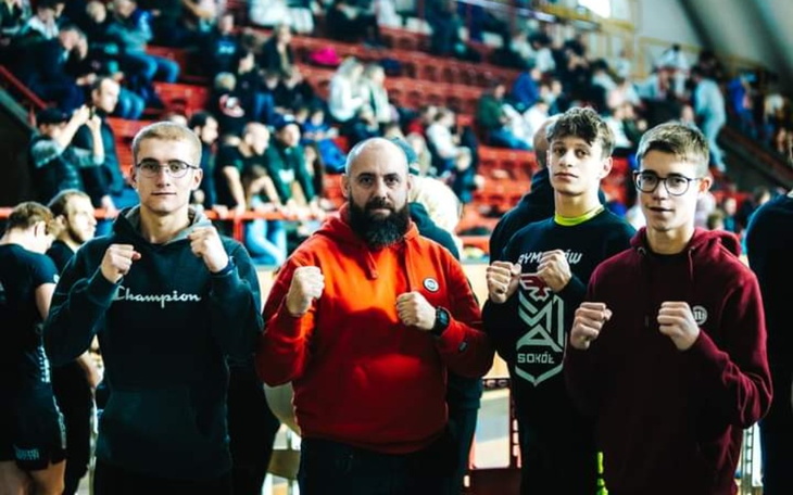 Grupa młodych ludzi w strojach sportowych, pozująca do zdjęcia.