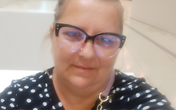 Kobieta w okularach, uśmiechająca się do kamery.