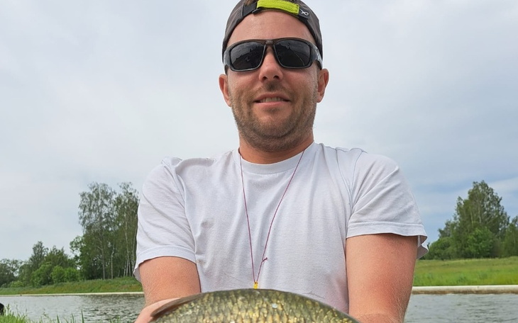 Mężczyzna z okularami przeciwsłonecznymi, trzymający dużą rybę.