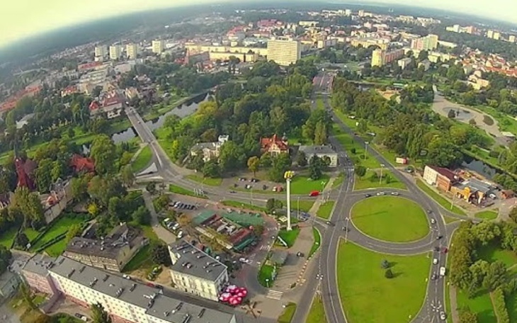 Widok na miasto z lotu ptaka, z zielonymi terenami i zabudową.