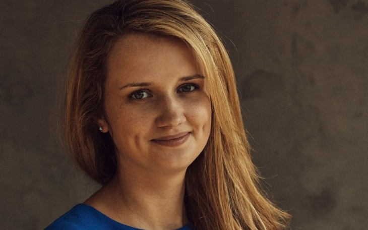 Portret uśmiechniętej kobiety w niebieskiej bluzce.