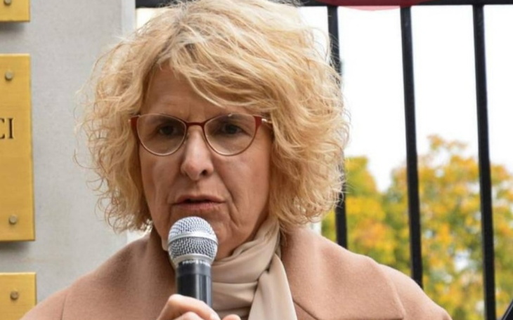 Kobieta przemawia do mikrofonu na zewnątrz.