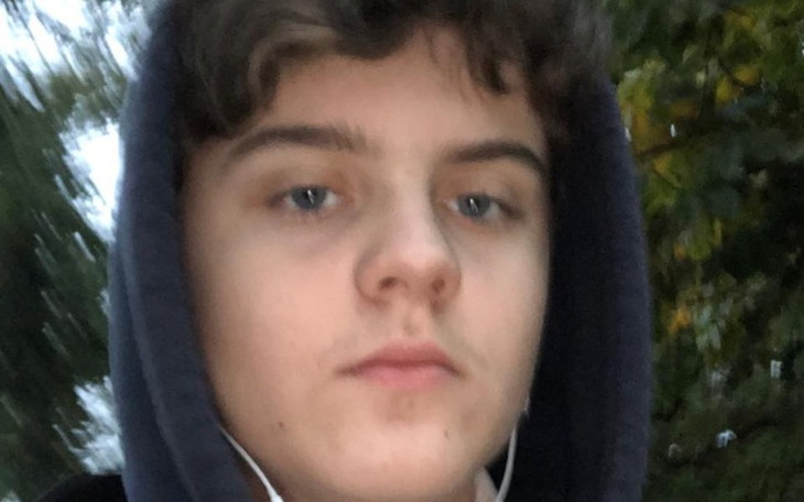 Młody chłopak na spacerze, z kapturem na głowie.